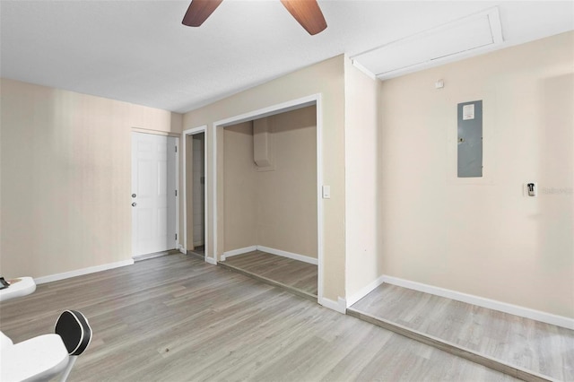 unfurnished bedroom featuring attic access, ceiling fan, baseboards, and wood finished floors