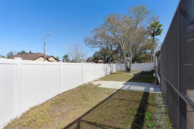 view of yard with glass enclosure, a patio area, and a fenced backyard