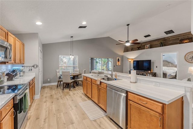 kitchen with sink, decorative light fixtures, vaulted ceiling, light hardwood / wood-style flooring, and stainless steel appliances