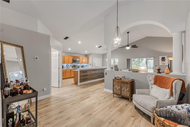 interior space featuring lofted ceiling, sink, ornate columns, light wood-type flooring, and ceiling fan