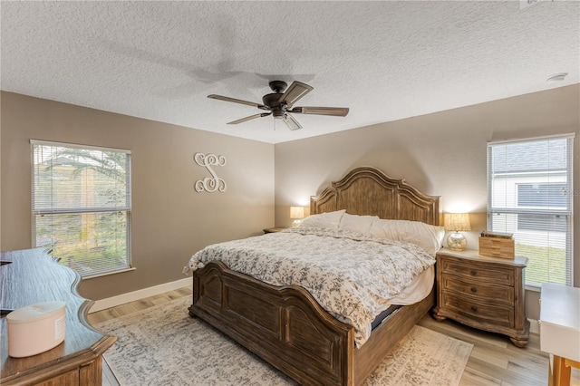 bedroom featuring ceiling fan, light hardwood / wood-style flooring, and a textured ceiling