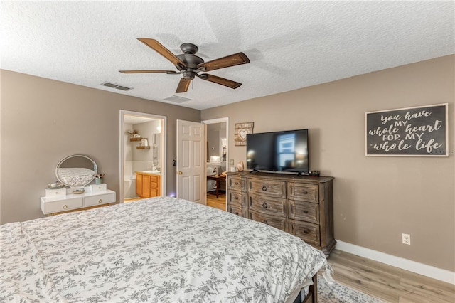 bedroom featuring ceiling fan, ensuite bathroom, light hardwood / wood-style floors, and a textured ceiling