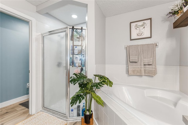 bathroom with wood-type flooring, plus walk in shower, and a textured ceiling