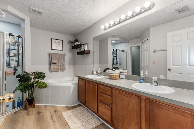 bathroom with vanity, independent shower and bath, hardwood / wood-style floors, and a textured ceiling