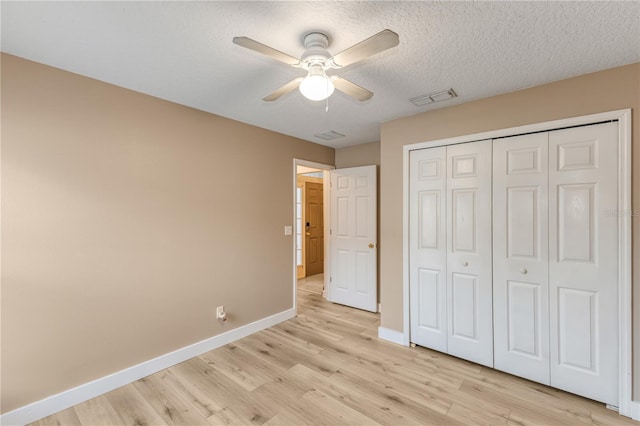 unfurnished bedroom with ceiling fan, a closet, a textured ceiling, and light wood-type flooring