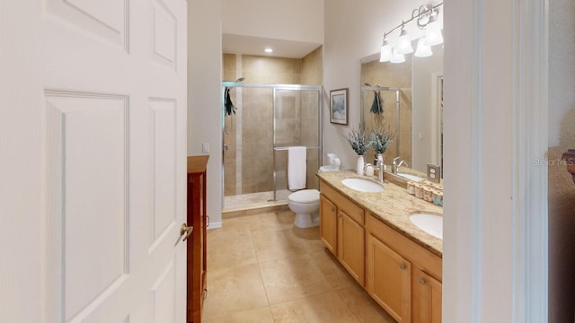 bathroom featuring tile patterned floors, toilet, a shower with door, and vanity