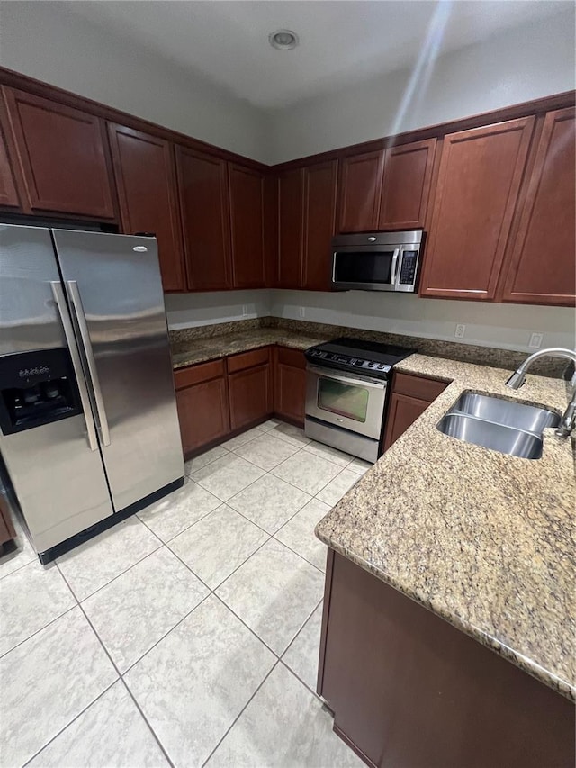 kitchen featuring stainless steel appliances, light stone countertops, sink, and light tile patterned floors