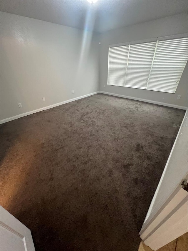 unfurnished room with dark carpet