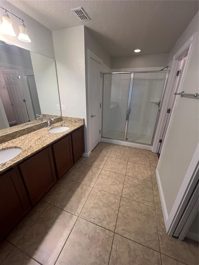 bathroom featuring vanity, tile patterned flooring, a shower with door, and a textured ceiling