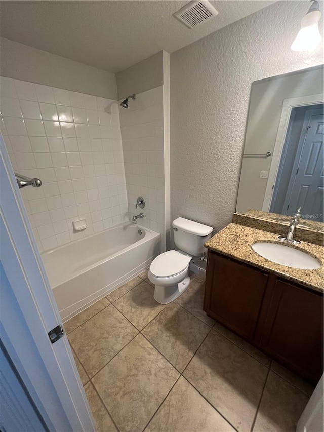 full bathroom featuring toilet, tiled shower / bath, a textured ceiling, vanity, and tile patterned flooring