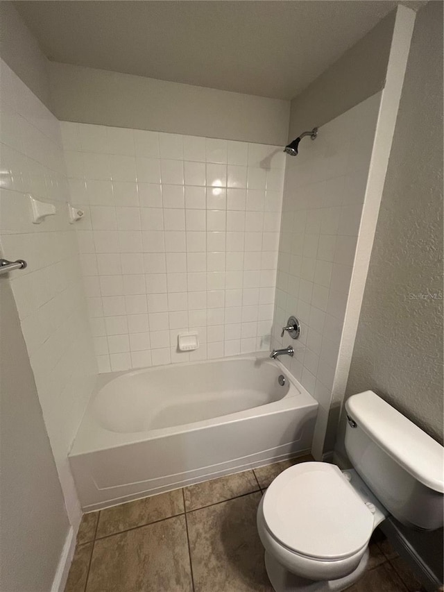 bathroom with tiled shower / bath combo, tile patterned flooring, and toilet