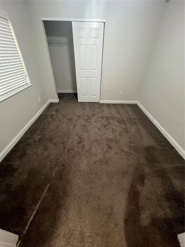 unfurnished bedroom featuring dark carpet and a closet