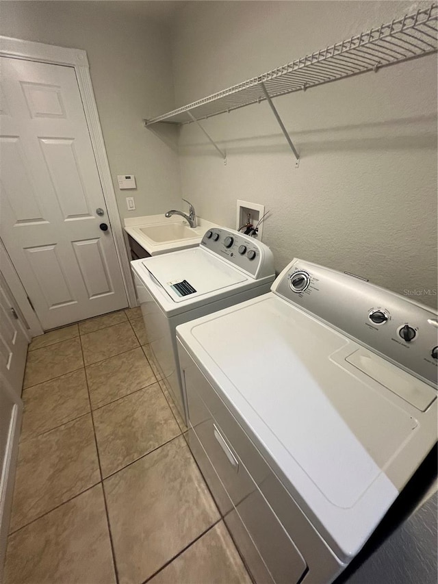 laundry room featuring washing machine and dryer, sink, and light tile patterned floors