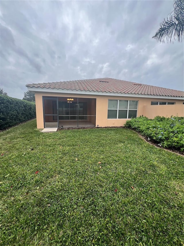 rear view of property with a sunroom and a lawn