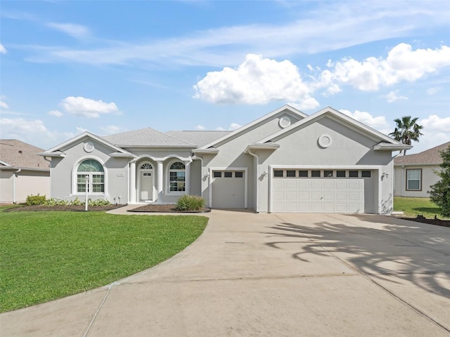 view of front of home featuring stucco siding, driveway, a front yard, and a garage