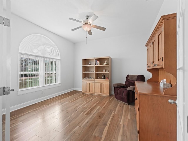 office area featuring light wood finished floors, ceiling fan, and baseboards