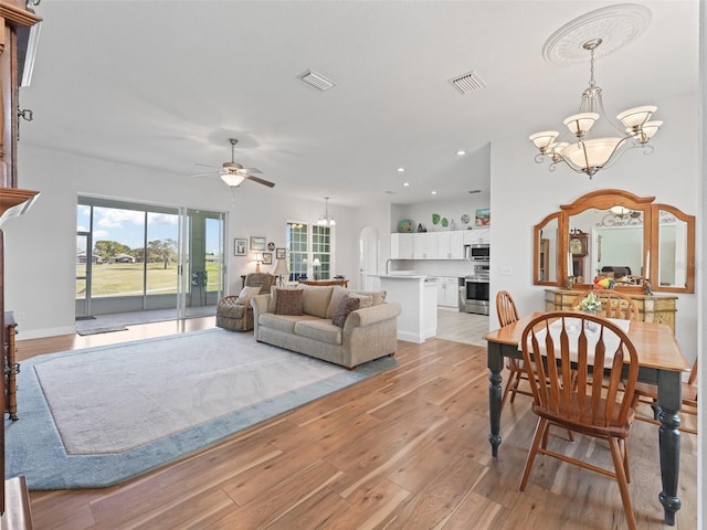 dining room featuring visible vents, ceiling fan with notable chandelier, recessed lighting, light wood-style floors, and arched walkways