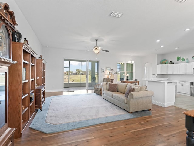 living room featuring recessed lighting, visible vents, wood finished floors, and ceiling fan with notable chandelier