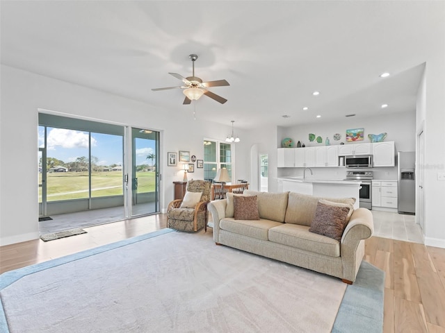 living room with baseboards, light wood finished floors, recessed lighting, arched walkways, and ceiling fan