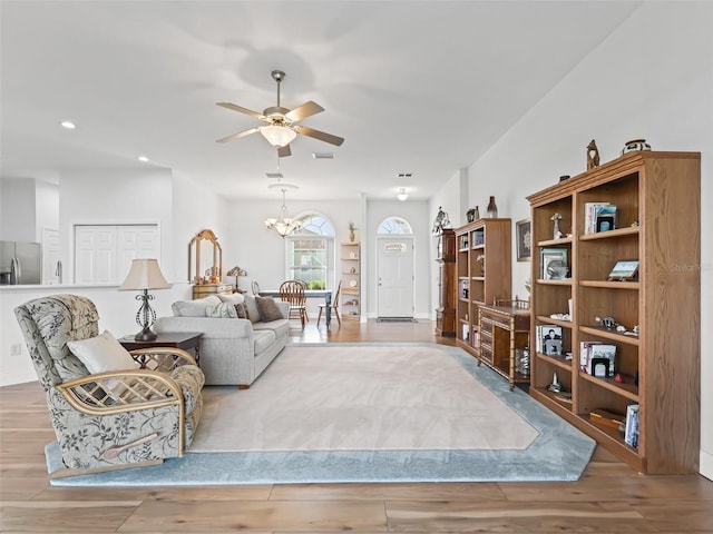 living area featuring recessed lighting, ceiling fan with notable chandelier, visible vents, and wood finished floors