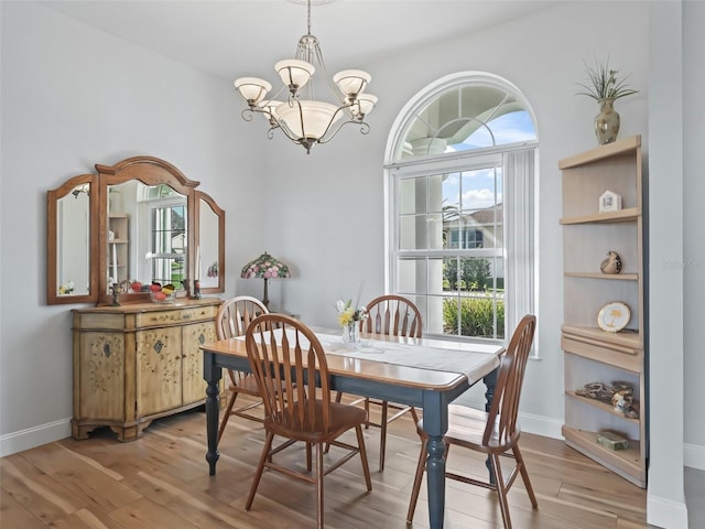 dining area featuring baseboards, a notable chandelier, and light wood finished floors