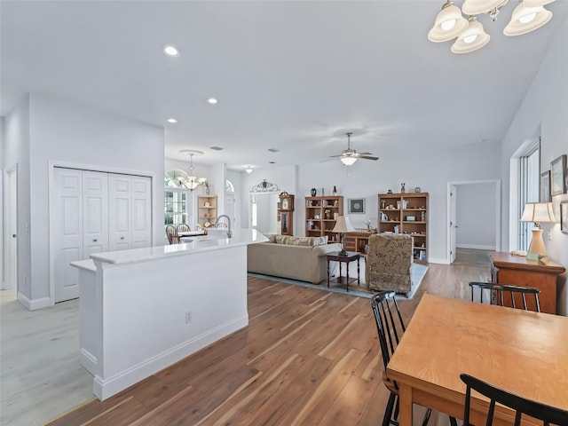 interior space with ceiling fan with notable chandelier, decorative light fixtures, recessed lighting, light wood-style floors, and light countertops