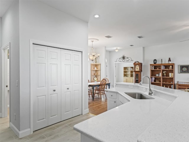 kitchen featuring visible vents, an inviting chandelier, wood finish floors, and a sink