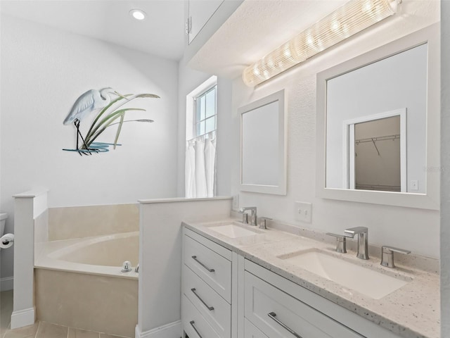 bathroom with a sink, a garden tub, recessed lighting, and double vanity