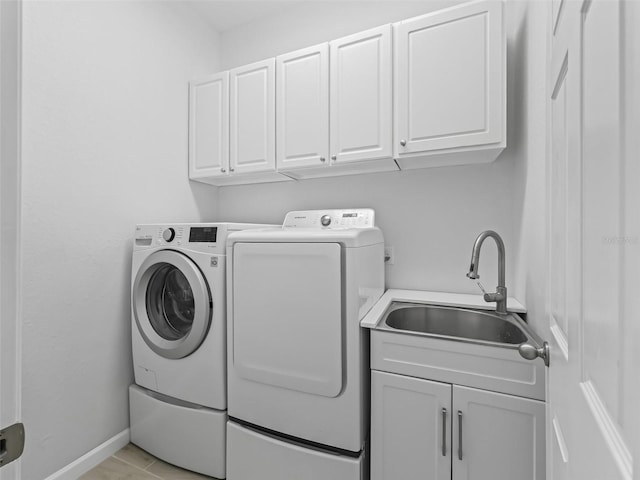 laundry area with a sink, baseboards, cabinet space, and independent washer and dryer