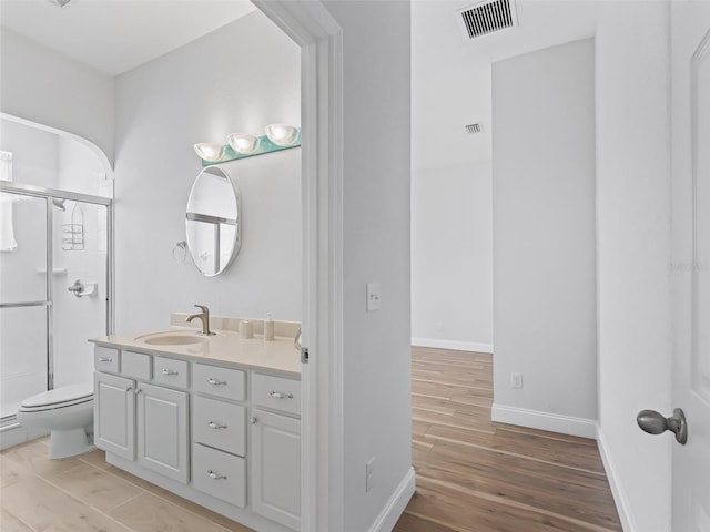 bathroom featuring visible vents, a shower stall, baseboards, wood finished floors, and vanity