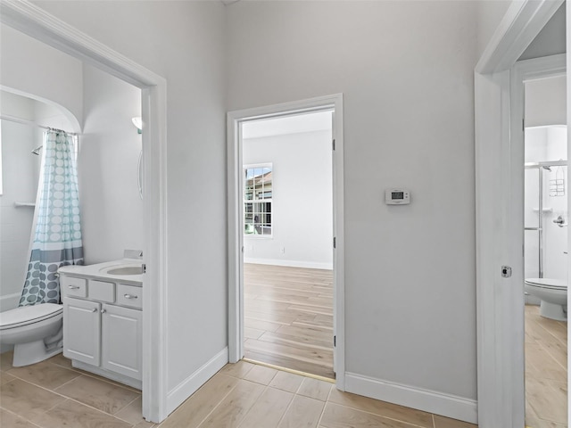 bathroom featuring curtained shower, toilet, and baseboards