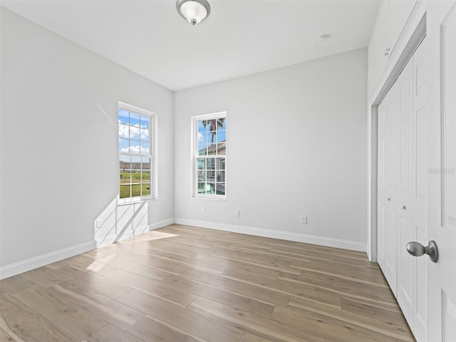 unfurnished bedroom with light wood-style flooring, baseboards, and a closet