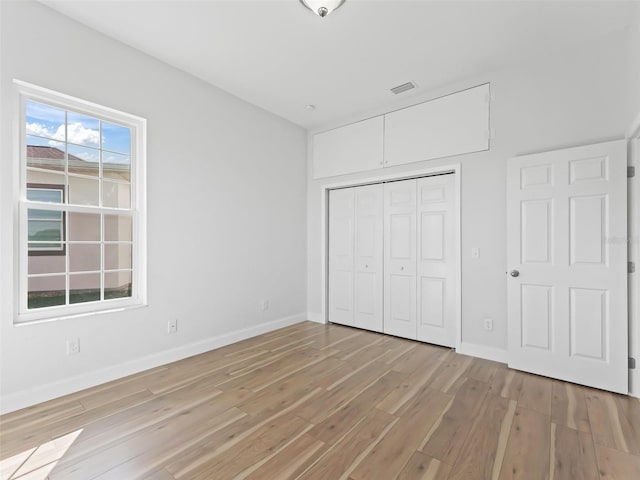 unfurnished bedroom featuring baseboards, light wood-type flooring, and a closet