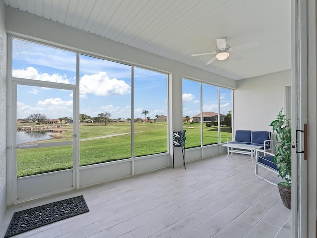 sunroom with a water view and ceiling fan