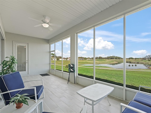 sunroom with a ceiling fan and a water view