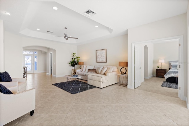 tiled living room with a raised ceiling and ceiling fan