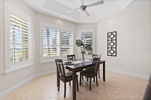 tiled dining space featuring a raised ceiling, a wealth of natural light, and ceiling fan