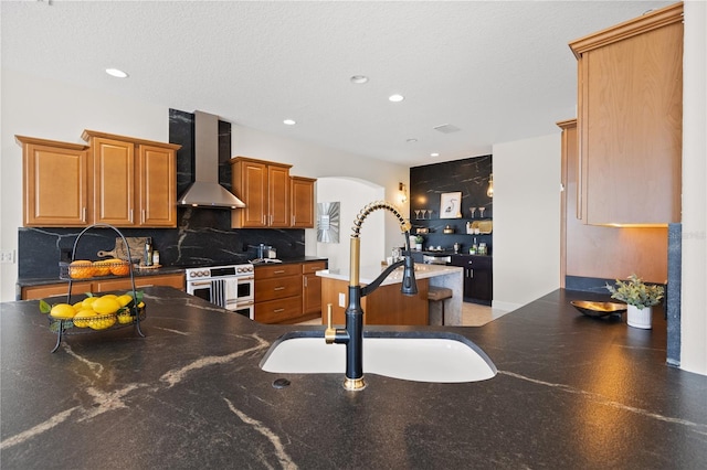 kitchen with sink, backsplash, double oven range, wall chimney range hood, and a textured ceiling