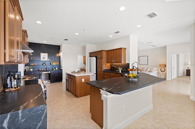 kitchen featuring ventilation hood, a kitchen island, high quality fridge, and backsplash