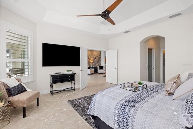 tiled bedroom featuring a raised ceiling and ceiling fan