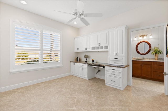 unfurnished office featuring ceiling fan, built in desk, sink, and light tile patterned floors