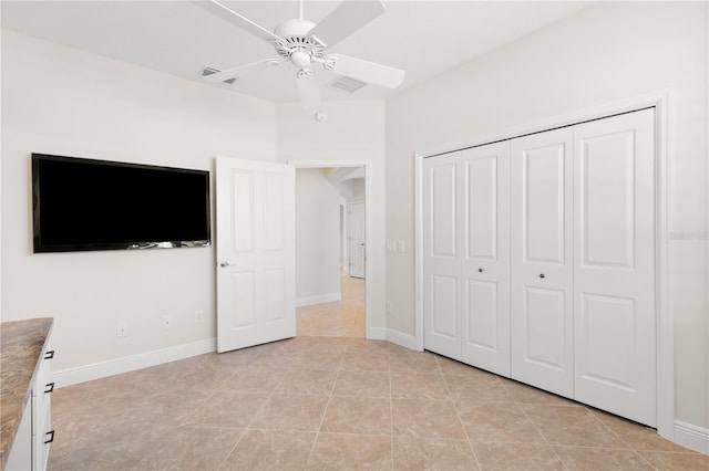 unfurnished bedroom with light tile patterned flooring, ceiling fan, and a closet