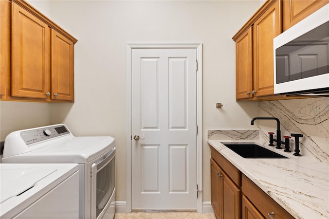 washroom with cabinets, washing machine and dryer, and sink