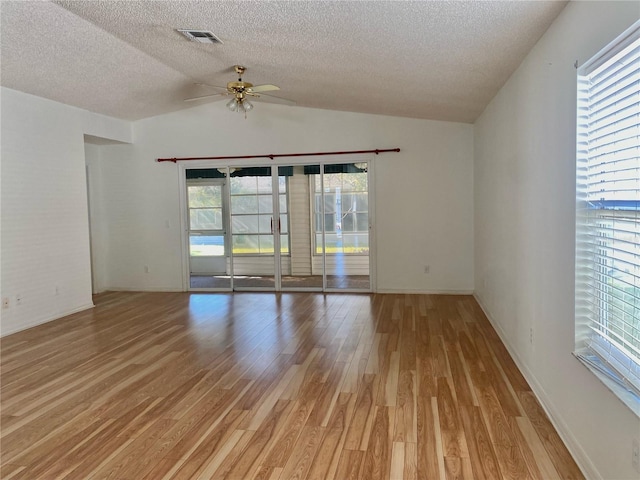unfurnished room featuring light wood-style flooring, a textured ceiling, a ceiling fan, visible vents, and lofted ceiling