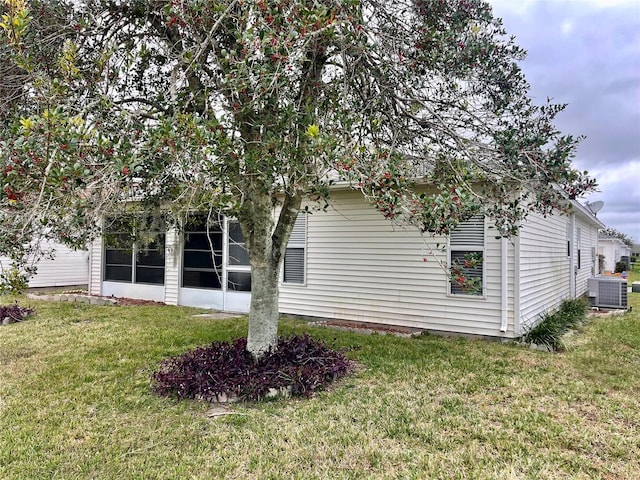 view of side of home with a yard, central AC unit, and a sunroom