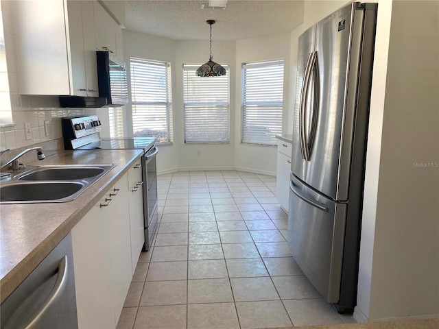 kitchen featuring a textured ceiling, white cabinetry, appliances with stainless steel finishes, light tile patterned flooring, and a sink
