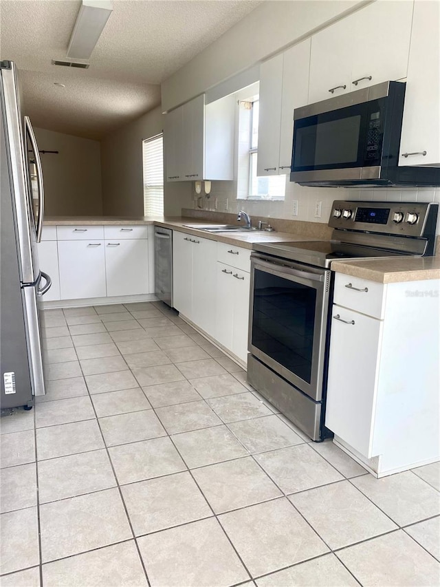 kitchen featuring a textured ceiling, white cabinetry, light tile patterned flooring, visible vents, and appliances with stainless steel finishes