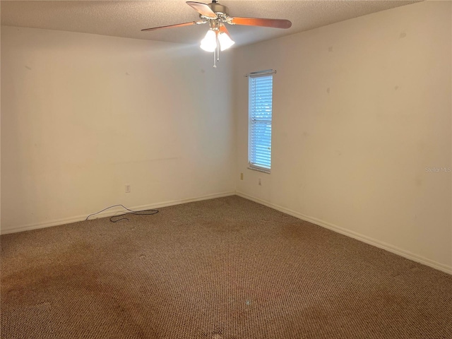 empty room with a textured ceiling, carpet flooring, ceiling fan, and baseboards
