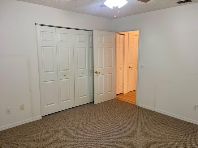 unfurnished bedroom with a closet, baseboards, carpet flooring, a textured ceiling, and visible vents