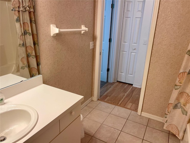 full bathroom with a closet, baseboards, curtained shower, vanity, and tile patterned floors
